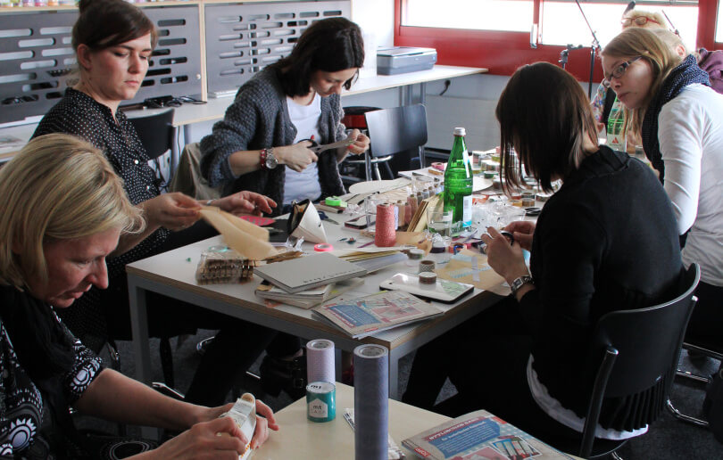Das Foto zeigt mehrere Frauen, die mit einem Klebeband, Scheren und anderen Materialien im Makerspace der Bibliothek Köln.